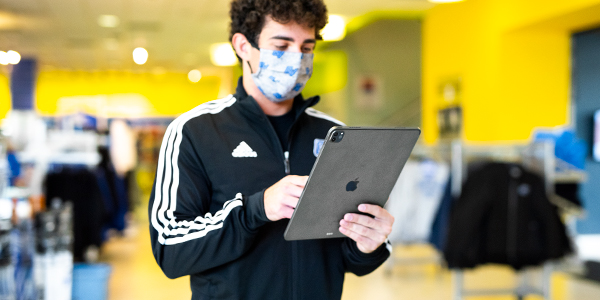 Student standing holding gray iPad.